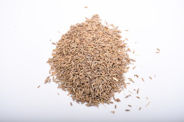 A molehill of a handful of cumin seeds scattered on a plain while background.