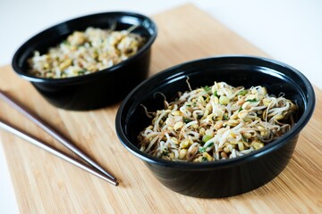 Close up black bowls with traditional Chinese sprouts salad. Healthy vegetarian eating. Green sprouts salad. Chinese cuisine.