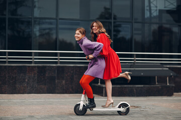 Two young women riding on electric scooter at the city © primipil