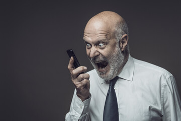 Angry senior businessman shouting on the phone