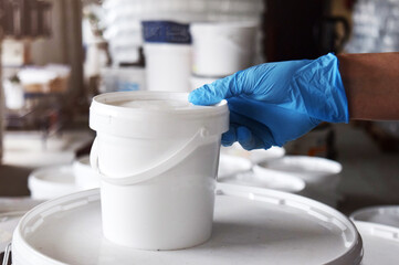 A man in blue gloves holds a can of paint in his hand. Paint production.