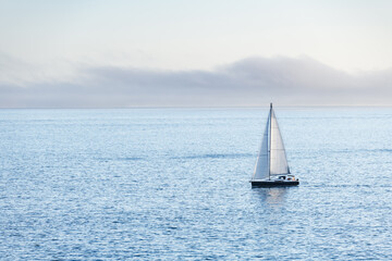 Fototapeta premium A lonely boat sails away from Ons Island in the Ria de Pontevedra in Galicia at dusk.