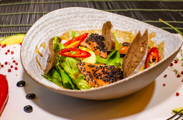 Salmon fillet salad with fried spinach, black sesame seeds and black bread. Selective focus. Super short focus