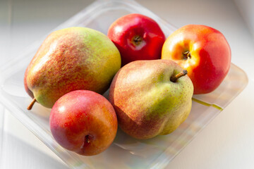 Autumn fruits on a plate. Pears, apples and plums are stacked in a plate. Selective soft focus. Healthy organic food.