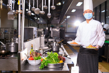 Male chef cooking in the restuaranr kitchen with his team.