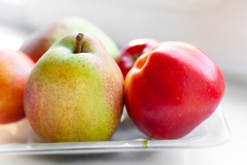 Close-up autumn fruits on a plate. Pears and apples are stacked in a plate. Selective soft focus. Healthy organic food.