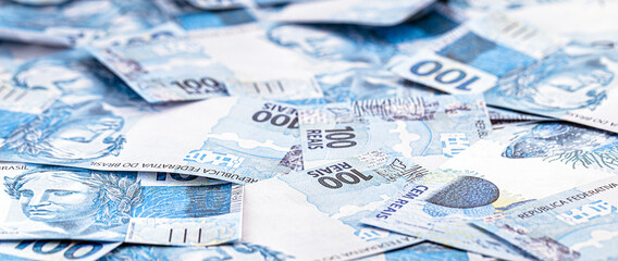 many banknotes of 100 Brazilian reais thrown, fallen, concept of brazil's financial crisis and economic chaos