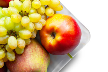 Close-up ripe autumn fruits isolated on white background. Juicy pears, red apples and grapes are stacked in a plate. Selective soft focus. Healthy organic food.