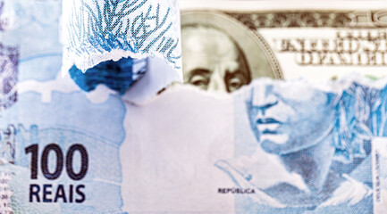 100 reais banknote hidden behind an American hundred reais bill. Concept of loss of value of the Brazilian real, Brazilian economy falling