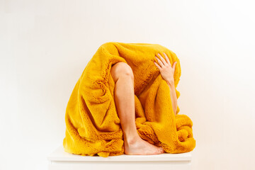 Person wrapped in yellow fluffy fabric, weird body parts are visible from beneath the bright...
