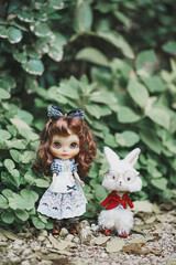 Wonderland. Cute dolls of a girl in maid dress checked pattern and a white rabbit doll in red suit.