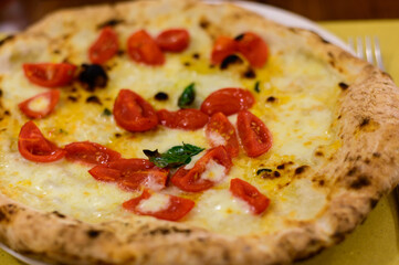 Eating of Italian pizza with mozzarella cheese, small red tomatoes and fresh basil