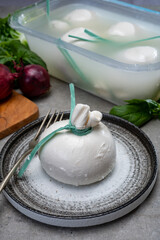 Eating of fresh handmade soft Italian cheese from Puglia, white balls of burrata or burratina cheese made from mozzarella and cream filling in container with water