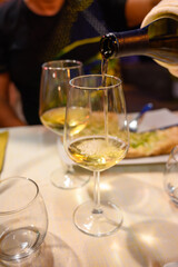 Pouring in glass  cold dry white wine in outdoor cafe at night in Italy