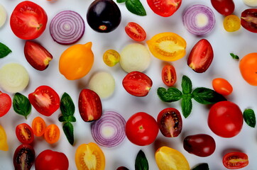 lots of tomatoes, onion slices and basil leaves isolated on a white background