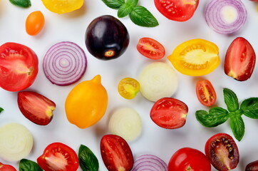 lots of tomatoes, onion slices and basil leaves isolated on a white background
