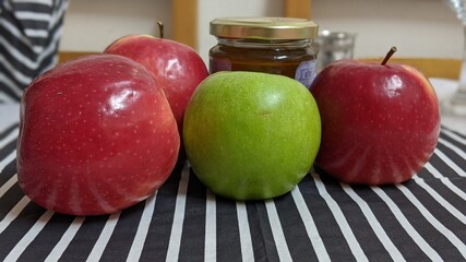 Red and green apples with a honey jar on black and white napkin. Jewish new year's holiday traditional food.