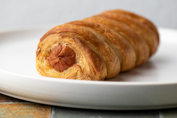 one sausage roll on a white plate 