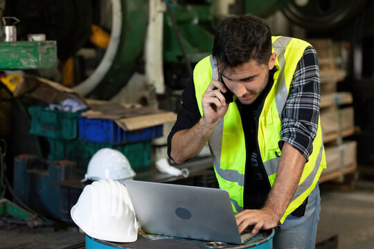 handsome engineer man or factory worker using smartphone and laptop computer for talking about work