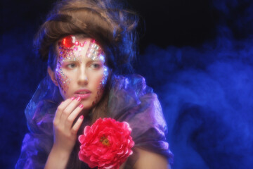 young woman with creative make up holding flowers