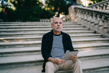 Concentrated senior man sitting on stairs in park