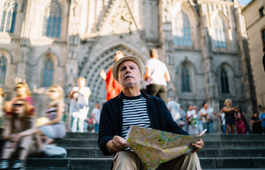 Serious old tourist with map on cathedral steps