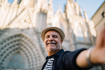 Cheerful man taking selfie against historical building