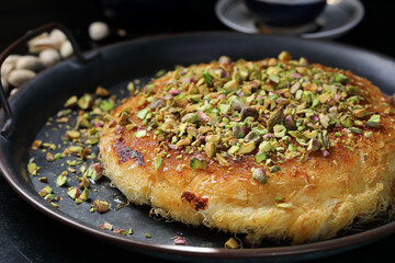 Kanafe arabic dessert with green almonds. Traditional arabian Kanafe cake with Kadaif hair noodels with soft focus. 
Eastern cookies beautifully served on metal plate. 
