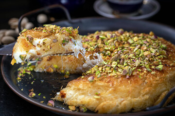 Kanafe arabic dessert with green almonds. Traditional arabian Kanafe cake with Kadaif hair noodels with soft focus. 
Eastern cookies beautifully served on metal plate. 
