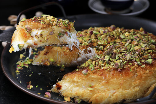 Kanafe arabic dessert with green almonds. Traditional arabian Kanafe cake with Kadaif hair noodels with soft focus. 
Eastern cookies beautifully served on metal plate. 
