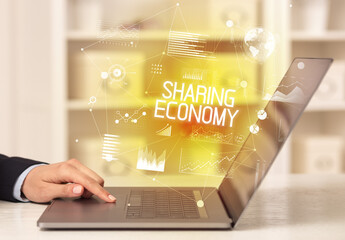 Side view of a business person working on laptop with SHARING ECONOMY inscription, modern business concept