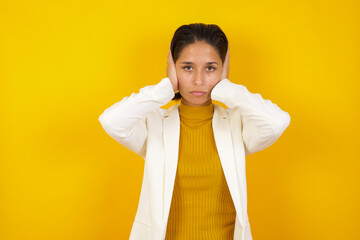 Woman plugging ears with hands does not wanting to listen hard rock or loud music. European Young  female ignoring noise or din covering her ears with hands avoiding loud sounds at street.