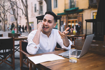 Excited ethnic man talking on smartphone