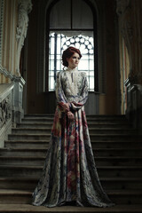 Naklejka premium woman in elegant dress posing on stairs