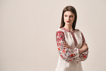 Young beautiful brunette girl wearing gorgeous ethnic style embroidered shirt, modern derivative from traditional Ukrainian vyshyvanka design. Fashion model in studio.
