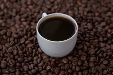 Hot black coffee in white cup on the coffee beans background ,
