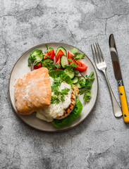 Burger with chicken cutlet, mozzarella cheese and mayonnaise mustard sauce and vegetables salad on a grey background, top view