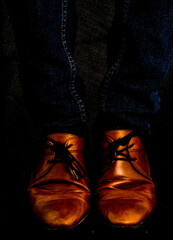 Leather dressed cognac brown shoes on dark blue jeans