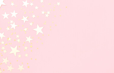 Pink pastel festive background with shining golden confetti in shape of stars.