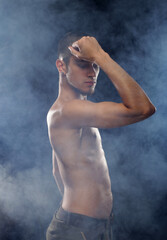 Fototapeta na wymiar Portrait of a muscular male model against dark background with