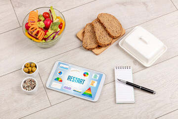 Fototapeta na wymiar Organic food and tablet pc showing RESTART inscription, healthy nutrition composition