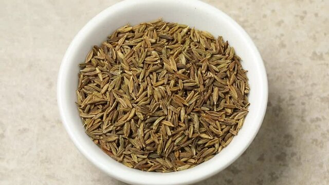 White bowl with dried cumin seeds close up