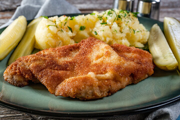Pork chop served with mashed potatoes and pickled cucumber.