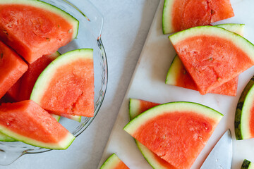 Watermelon slices on a plate and cutting board, close up view from above