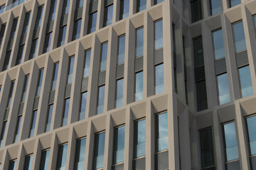 Close-up of the modern concrete glass facade of a business skyscraper with reflection of the blue sky in the windows