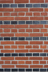 Old rural brickwork facade with red and black bricks - vertical background
