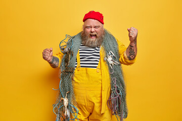 Annoyed emotional male sailor or professional seaman has sea cruise poses with fishing net raises...