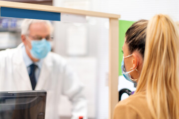 Pharmacist wearing a covid coronavirus mask talking to a customer