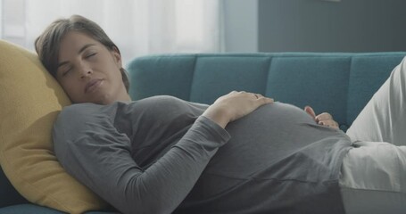 Tired pregnant woman sleeping on the sofa