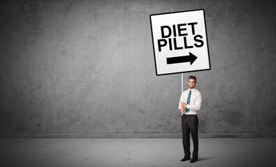 Obraz premium business person holding a traffic sign with DIET PILLS inscription, new idea concept